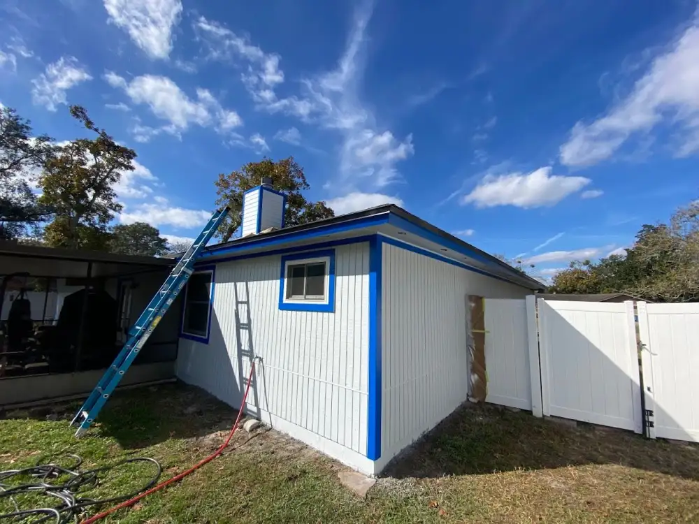 White-sided home exterior with bright blue trim beneath a blue sky