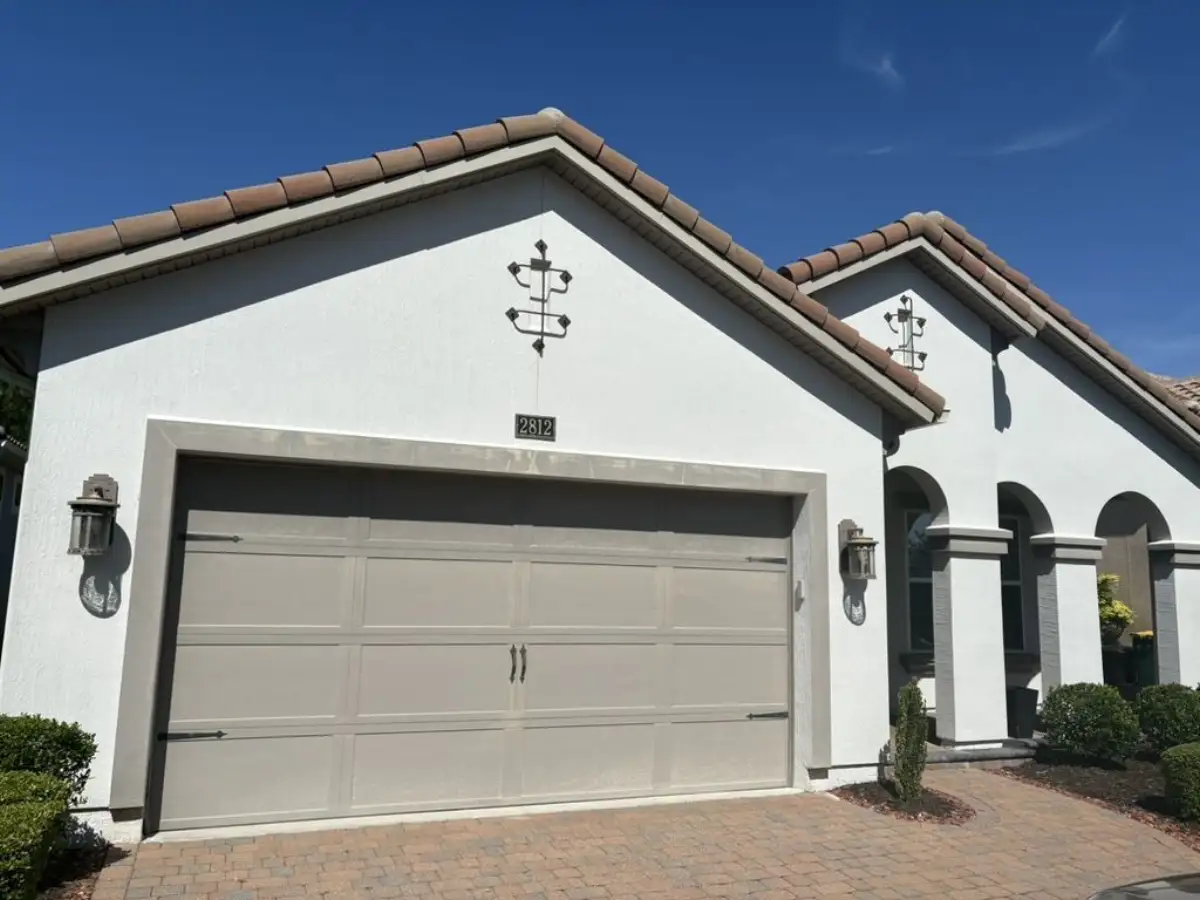 Textured home exterior after painting, with a bright white finish and contrasting gray garage trim and columns