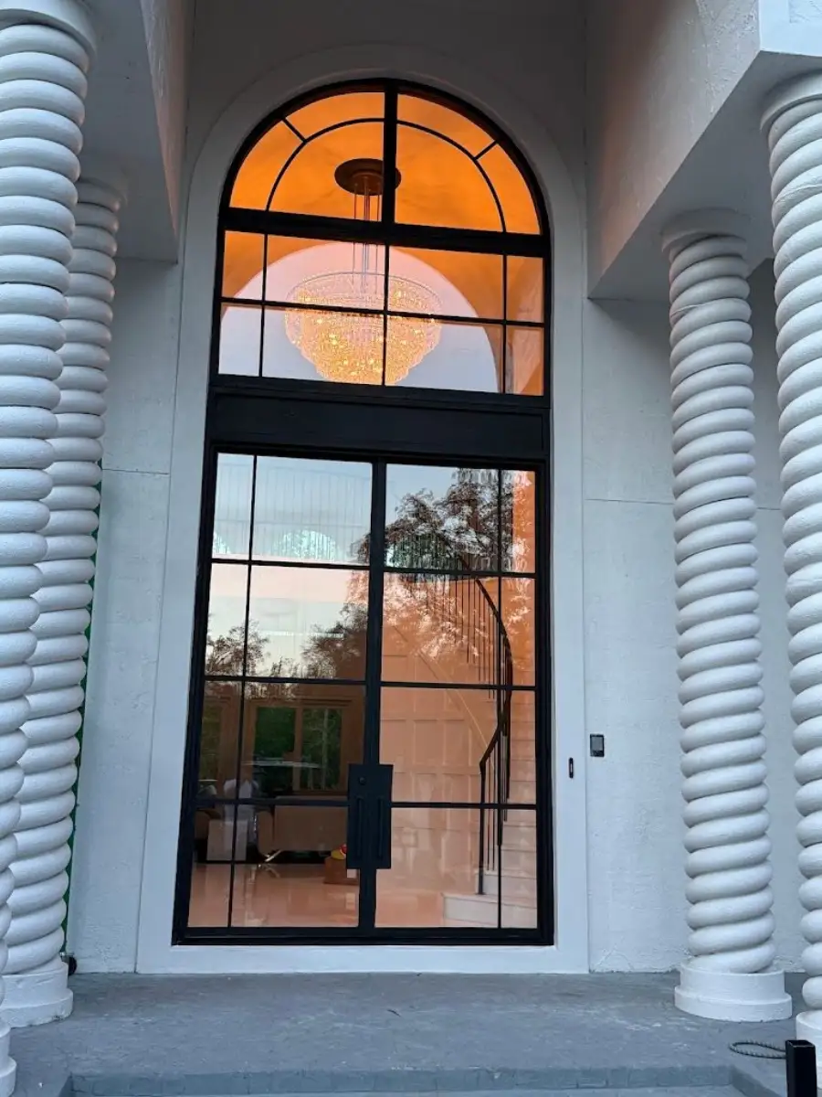 Black-framed arched glass entry between white spiral columns