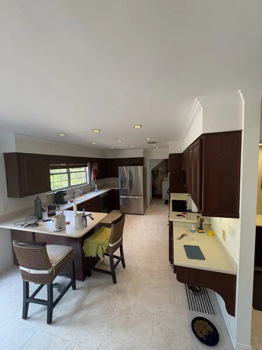 Completed kitchen interior with light walls and white crown molding surrounding dark wood cabinets