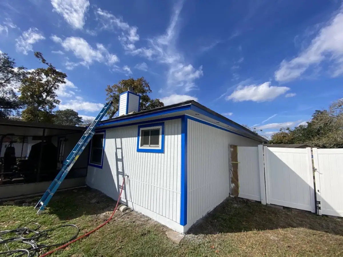 Light home exterior with vivid blue trim and a ladder beside the chimney