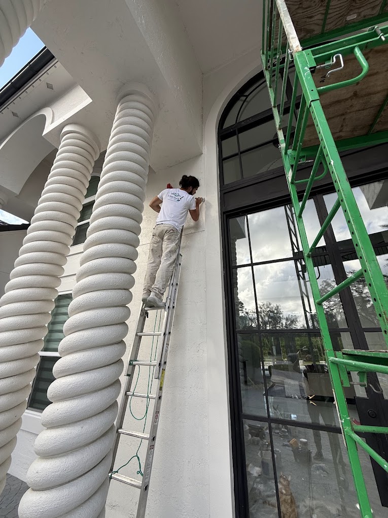 Painter working from ladder on commercial columns