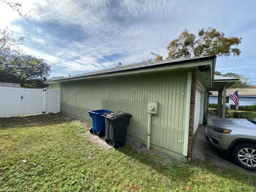 Green residential exterior with matching trim beside a driveway